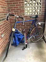 Full view of blue vintage Raleigh Grand Prix bike showing frame, drop handlebars, saddle, rear rack, and pump placed beside it.