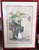 Full view of the vintage lithograph framed in a red frame with double matting, depicting Minnesota North Stars goalie Gilles Meloche.