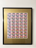 Framed sheet of 40 uncut Elvis Presley stamps with gold mat and black metal frame hung on white wall.
