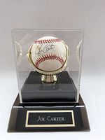 Signed baseball in clear acrylic display case with gold-tone stand and 'Joe Carter' name plaque