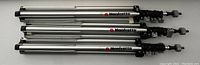 Three folded Manfrotto lighting stands placed horizontally showing logo on side of stands.