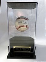 Signed baseball displayed inside clear acrylic display case with black base and "Rollie Fingers" plaque visible.