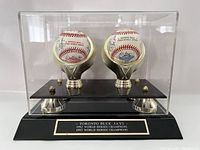 Acrylic display case containing two signed baseballs on gold-tone holders