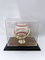 Overall view of signed baseball inside clear acrylic display case on wooden base