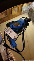 Full view of blue Mastercraft electric drill with attached black power cord and label tag.
