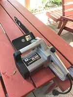 Full view of Mastercraft MC3000 electric chainsaw on a wooden picnic table, showing the body, handle and blade.