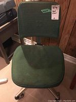 Front view of the green fabric desk chair with chrome frame showing seat, backrest, and wear