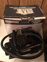 Air compressor inside original box showing coiled hose and gauge.