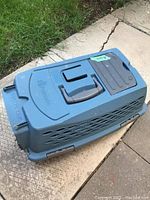 Top and side views of the blue Petmate cat carrier showing ventilation slits, a handle, and rust spots on the cage door area.