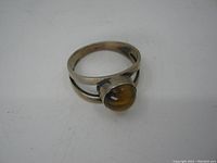 Front side view of the sterling silver ring displaying the tiger's eye stone cabochon and split band.