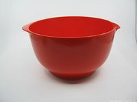 Front side view of the red plastic mixing bowl showing its pour spout and wide opening