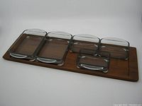 Full view of teak tray with four glass inserts placed inside, showing right side missing one small insert.