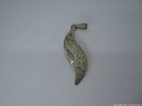 Front view of curved silver pendant with Indigenous designs and cut-outs