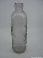 Front view of the old glass bottle with embossed lettering and purple tint.