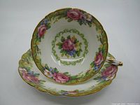 Top angle showing teacup rested on saucer with floral tapestry rose pattern inside both pieces, gold trim visible.