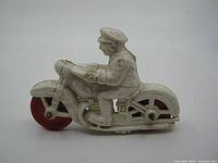 Side view of white rubber police motorcycle toy showing detailed police officer figure and red rear tire