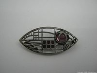 Top down front view of the brooch showing the openwork metal design and purple cabochon stone