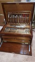 Open wooden flatware chest showing vertical knife storage and cutlery trays
