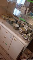 Stacks of yellow-ground porcelain plates and bowls on white cabinet shelf
