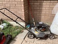 Side view of the Craftsman gas lawn mower with black handle and gray metal deck on pavement outdoors.
