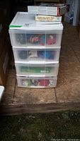 Full view of the white four-drawer plastic storage unit with toys inside drawers and two boxed games on top.
