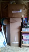 Two stacked cardboard boxes containing the stuffed toys in a shed area.