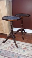 Pair of wooden side tables with three legs each, standing on a rug near furniture.