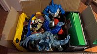 Overhead view of box with colorful plastic action figures including a large blue shark figure, a muscular werewolf figure, and other assorted toys