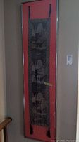 Full view of framed Asian inspired fabric art hung on wall showing entire piece and hanging straps.
