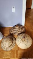 Three Asian style straw hats placed on floor showing different shapes and weaving styles.