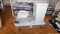 Photo showing Sterilite under bed storage bin with wheels and lid, packed with clear hanging closet organizers and storage bags on top.