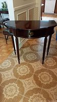 Front view of the hall table showing the half-moon shape, central drawer with brass pull, and fluted legs.