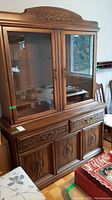 Full view of the wooden hutch showing top glass door cabinet and bottom drawers and cupboards with carved details.