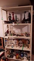 Front view of metal shelving unit loaded with various decorative items for scale and showing shelf levels and structure.