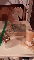 Three stone items on shelf: horse figurine lighter, trinket box, and Nefertiti bust base.
