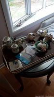 All porcelain pieces and metal tray arranged on table by window.