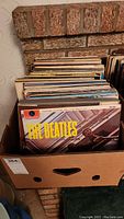 Photo of box filled with vinyl LP records showing The Beatles album at front.