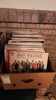 Box of vinyl LP records seen from the side with visible spines, including Andy Williams album on front