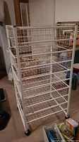 White metal wire storage rack on caster wheels, showing full profile from an angle.