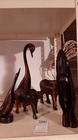 Five carved wood animal figures: two swans with long necks, one bird, and two bulls. Figures are polished dark wood with visible wood grain.