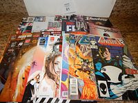 Photo showing a collection of over 25 comic books with various publisher logos and characters including Punisher, Deadpool, John Wick, and Shadow.