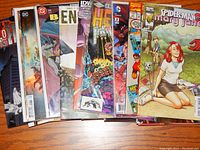 Stack of 25 or more comic books from various publishers including DC, Marvel, IDW, Dynamite, visible comic titles include Spider-Man Mary Jane, Ben 10, and Hellboy.