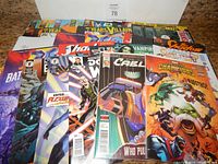 Photo of 25+ comic books spread out with visible titles including Batman, Cable, Champions and more