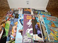 Multiple comic books stacked with fronts visible, showing titles from DC, Marvel, IDW, Dynamite and others.