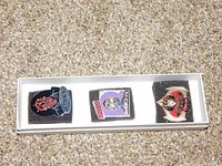 Close-up photo of three Star Trek character enamel pins in white foam padding box. Pins depict Darth Maul, a character with a blue background, and a Star Trek insignia figure.
