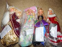 Four vintage Barbie dolls individually bagged with handwritten tags identifying each doll, dressed in period-themed gowns for Peppermint Princess, Midnight Princess, Spring Bouquet, and Happy Holiday characters.
