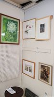 Five framed art pieces displayed on two adjacent walls including botanical and vintage artworks.