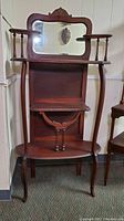 Front view of vintage French wooden etagere shelf with beveled mirror backsplash and multiple display shelves.