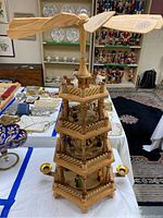 Full view of the three-tier hexagonal wooden Christmas carousel music box with spinning center and windmill top rotor blades.