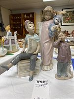 Lot image showing all three NAO figurines arranged together on a white cloth, highlighting their relative sizes and details.